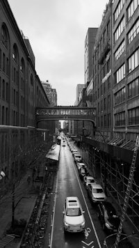 a black and white photo of a street with cars parked on it